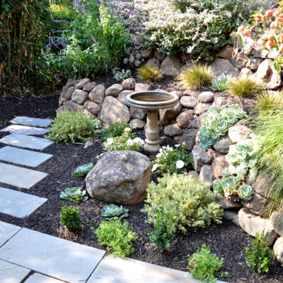 Arch cut stones with black mulch and moss rock boulder